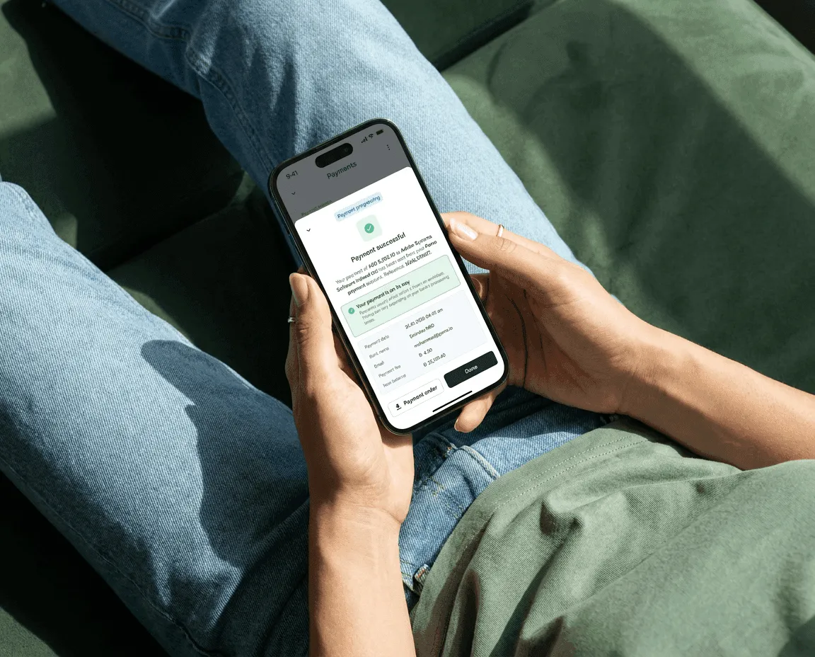 Someone holding a phone showing a payment successful screen in the Pemo app